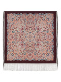Decorative throw shawl with intricate pattern and fringes on a white background. Warm and beautiful, this large brown shawl in natural merino wool features a Slavic traditional design in light blue and red. A woman wearing it can wrap it easily, with soft texture and flowing fringe.