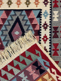 Close-up of a patterned Armenian rug with geometric designs in red, blue, and beige. The ornament is ethnic Armenian. It is not hand woven, it is machine made.
