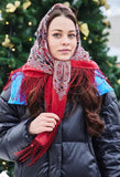 Woman wearing a red scarf and black coat in front of a decorated Christmas tree.