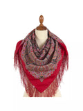 Red woolen oversized scarf with intricate patterns and fringes on a mannequin against a white background