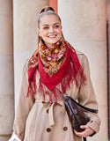 Made from natural sheep wool, this red fringed shawl reflects traditional Slavic style. A woman wears it gracefully, with yellow and pink peony flowers adding elegance.