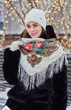 Made from natural sheep wool, this 100% merino wool shawl reflects traditional Slavic style. A woman wears it gracefully, adorned with a subtle herbal pattern in red, yellow, and green.