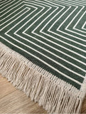 Green and beige striped rug with fringes on a wooden floor