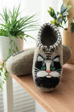 Woolen cat slippers on a table near the plant