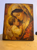 Handcrafted wooden Catholic icon of Virgin Mary holding Infant Jesus with gold leaf halos.
