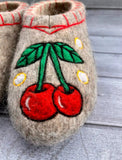 Felted slippers with cherry design on a wooden surface