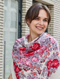 A Slavic woman wearing a large square merino wool scarf in white, red, and pink with a rose pattern and fringed edges.