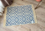 Patterned floral rug in gray and beige on a wooden floor with a chair leg visible