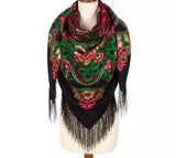Colorful patterned merino wool scarf with fringes and pink and green flowers on a mannequin against a white background