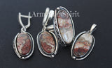 A set of sterling silver jewelry featuring crazy lace agate stones, including earrings, a ring, and a pendant, displayed against a dark background. The jewelry is one of a kind and made by Armenian artisans.