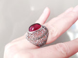 Large dome ring women, with oval quartz in red and marcasite, filigree herbal pattern on a woman white hand.