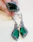A pair of long green marcasite earrings with intricate sterling silver designs, featuring teardrop-shaped green stones.

