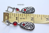 Long earrings with Armenian taraz ornament in silver and black with red transparent stone in the middle near the ruller which indicates 2 inches