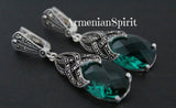 Pair of earrings with emerald green gemstones and marcasite silver designs on a black background, featuring 'Armenian Spirit' branding.