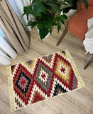 Patterned Armenian traditional rug on a wooden floor with a plant and chair in the background