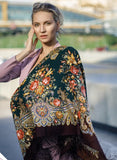 A woman wearing an extra-large merino scarf with a vintage-inspired herbal pattern in rich green and brown tones. The retro design is beautifully complemented by a soft, natural merino texture and finished with a silky fringe for timeless elegance.