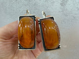 Expertly crafted by Armenian artisans, these unique earrings showcase a large rectangle of honey amber set in high quality sterling silver. With only one of its kind, this single copy of jewelry is a true statement piece. Upgrade any outfit with this one-of-a-kind, exclusive treasure.
