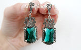 Intricately detailed Tudor Renaissance silver dangle earrings with large, shiny green emerald faceted centerpieces and borders of sparkling marcasites, ideal for luxury cosplay with Armenian Spirit title.