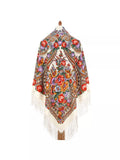 An extra-large white merino scarf inspired by traditional Slavic patterns, featuring herbal motifs in red and yellow. The vintage look is balanced with luxurious natural merino and a delicate silky fringe for timeless appeal.