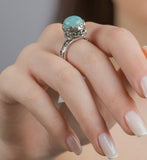 Close-up of a hand wearing a silver ring with a light blue larimar gemstone.