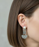 Pearl Armenian earrings with silver lace filigree design worn by a person with brown hair.