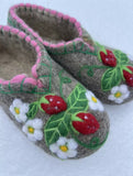 Pair of felted slippers with floral designs on a white background