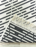 Black and white striped rug with tassels on a marble surface