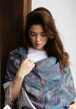 Woman wearing a patterned merino wool gray shawl against a neutral background. Close-up view of a premium merino wool scarf, highlighting the woven gray and ivory geometric Slavic motifs accented with deep blue tones.