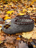 Large size gray woolen slippers for men on a ground with fall leaves.