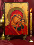 A traditional Orthodox pine wood icon of the Virgin Mary and Christ Child on a stand next to a burning candle.
