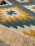 Close-up of a patterned rug with geometric design and fringes.