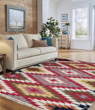 Living room with a patterned Armenian fringed rug in red and yellow near a  beige sofa, and wooden walls.