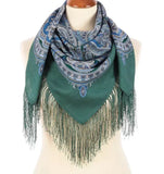 Green Slavic scarf with paisley pattern and fringes on a mannequin against a white background.