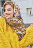 Woman wearing a colorful headscarf in yellow with light blue and purple field flowers. The material is merino wool.