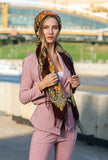 Woman in a pink outfit with a colorful woolen brown and dark green floral head shawl standing outdoors.