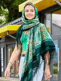 A woman wearing a rich green head shawl with yellow patterns looks graceful and confident. The colors are bold yet balanced. The green silky fringe looks nicely in mix with Slavic patterns.