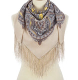 Cashmere woolen like scarf with paisley pattern in pale gray and lemon yellow and fringes on a mannequin against a white background