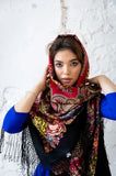 A cozy winter fashion shot of a woman wearing a heavy woolen head shawl with intricate paisley ornaments and large vintage rose flower prints.