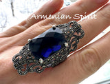 An extra big sterling silver ring with a navy blue topaz stone and Marcasite accents, displayed on a person's hand.