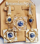 This large jewelry set is made of white non-blackened sterling silver and blue lapis lazuli gemstones round cabochon. The ring is square with geometric pattern. The earrings concsist of several geometric parts. The jewelry is gold plated. The earrings are quite long almost till shoulder.