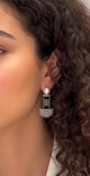 Close-up of a woman wearing star-shaped Armenian earrings with a blurred background