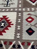 Close-up of a woven rug with a Southwestern geometric pattern in taupe, cream, red, and black.