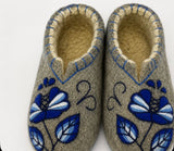 Woolen slippers with blue flower embroidery and  blue trim on a white surface