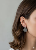 Close-up of a person wearing a silver coat of arms Armenian earring with a pearl on a neutral background
