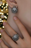 Close-up of a person wearing Armenian silver earrings and ring with blurred lights in the background