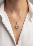 Silver sun pendant necklace on a white shirt