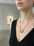 Person wearing a Sterling silver 925 rays necklace in an art gallery setting