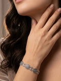 Close-up of a woman's hand wearing a silver coin details bracelet with Armenian taraz designs, touching her neck.
