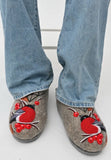 Gray woolen felted slippers with red and black bird design worn with blue jeans on a white background