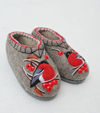 Pair of woolen gray slippers with embroidered red birds and berries on a white background